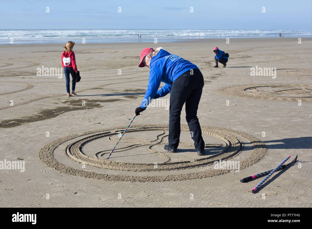 Un volontario che lavora su un grande labirinto di sabbia creato da Denny Dyke, a Heceta Beach in Firenze, Oregon, Stati Uniti d'America. Foto Stock