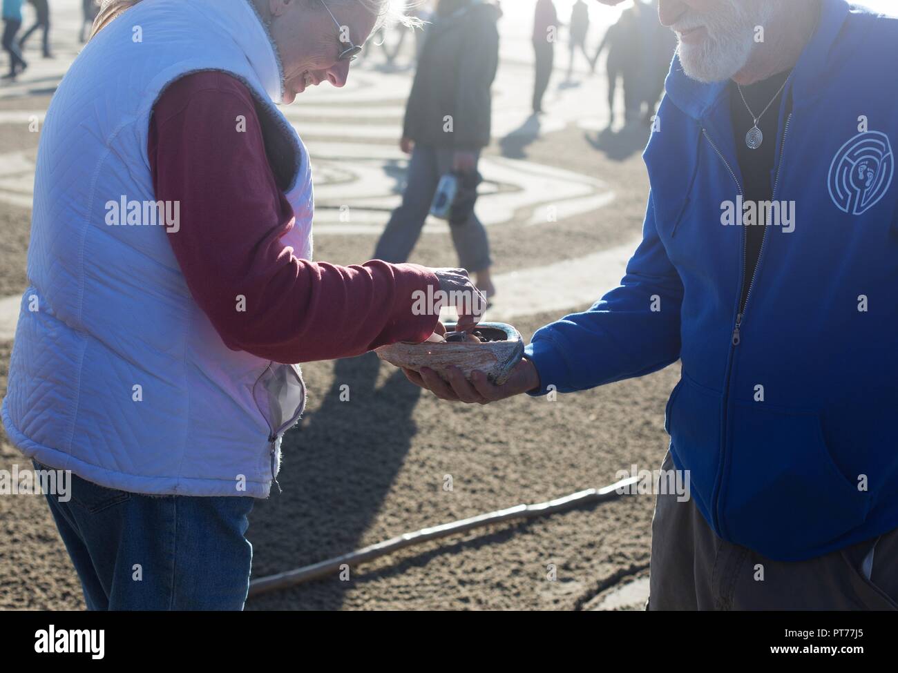 Sabbia artista Denny Dyke consegna ad un visitatore un 'dream rock' prima di entrare nel grande labirinto di sabbia ha creato, a Heceta Beach in Firenze, Oregon, Stati Uniti d'America. Foto Stock