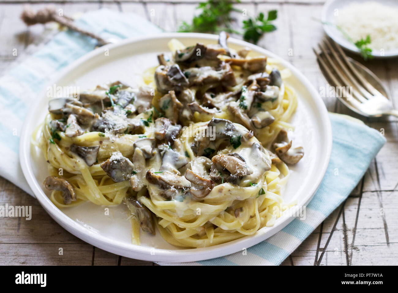 Tagliatelle con panna e funghi di bosco salsa in una piastra bianca su uno sfondo di legno. Stile rustico. Foto Stock