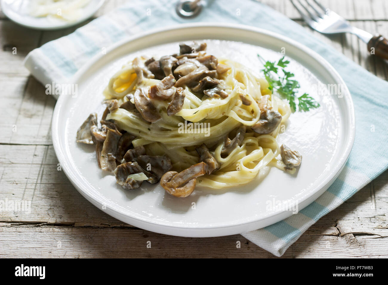 Tagliatelle con panna e funghi di bosco salsa in una piastra bianca su uno sfondo di legno. Stile rustico. Foto Stock