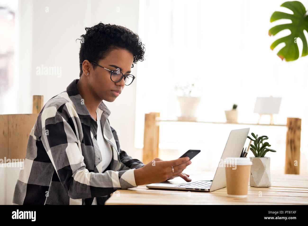 Fiducioso business donna a lavorare utilizzando il computer e il telefono in off Foto Stock