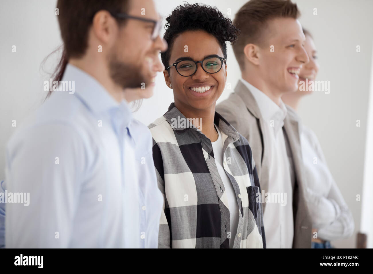 Donna africana con i colleghi in piedi sorridente in ufficio Foto Stock