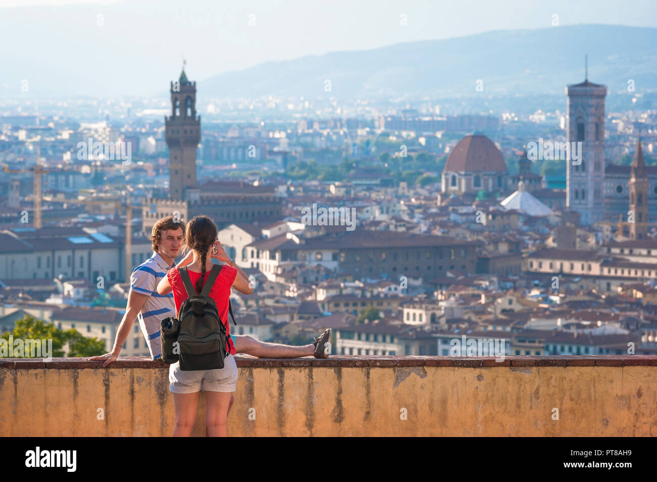 I turisti Firenze, su una terrazza a San Miniato al Monte una giovane donna fotografie il suo amico maschio contro lo sfondo della città di Firenze, Italia. Foto Stock