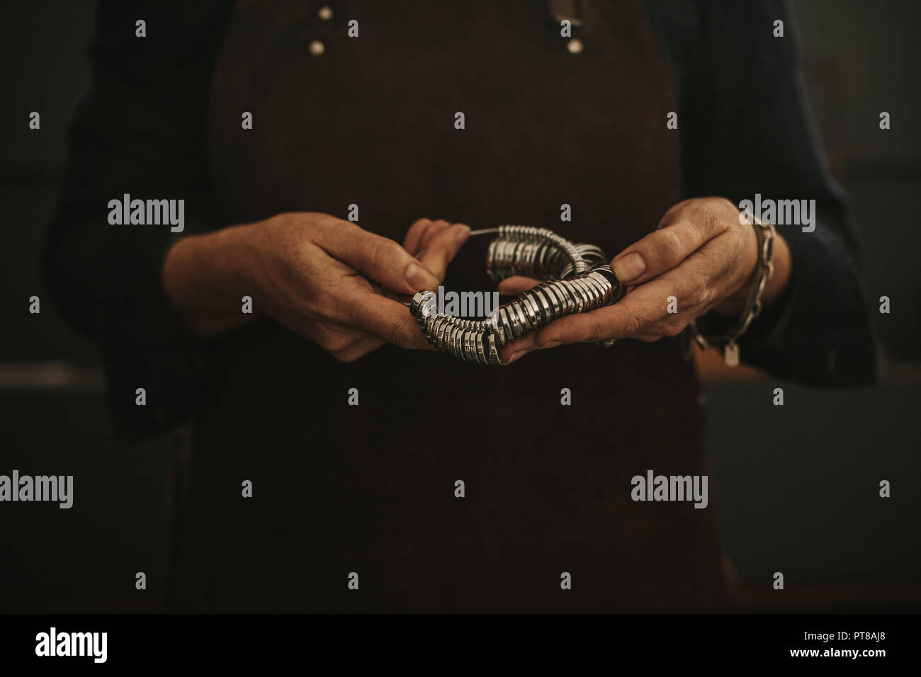 Close up donna gioielliere mani anello dito misuratore. Ritagliato colpo di gioielli femminili maker con calibro ad anello in officina. Concentrarsi sulle mani di jewe Foto Stock