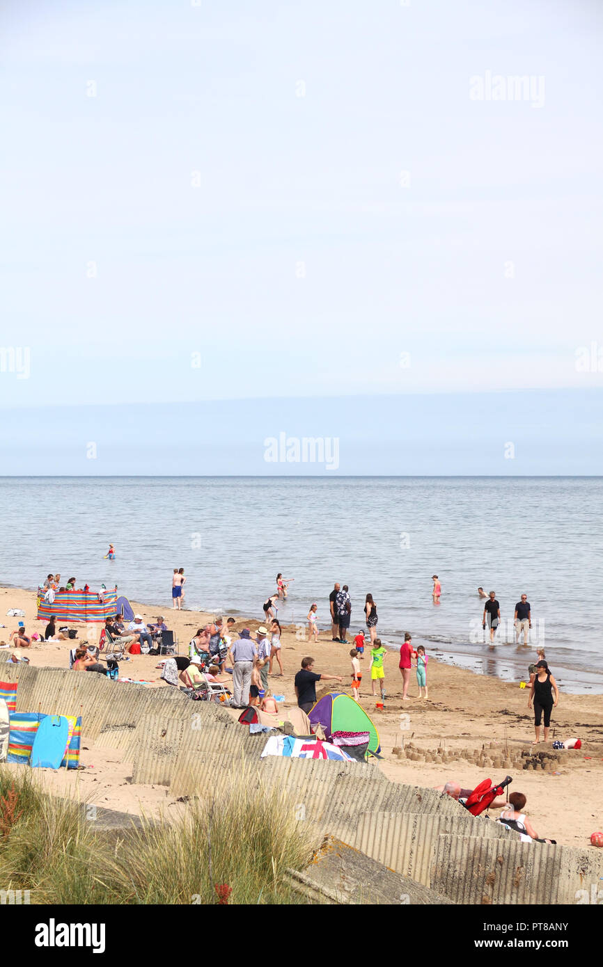 La folla di gente sulla spiaggia Alnmouth ad alta marea durante l'estate, Northumberland, Inghilterra Foto Stock