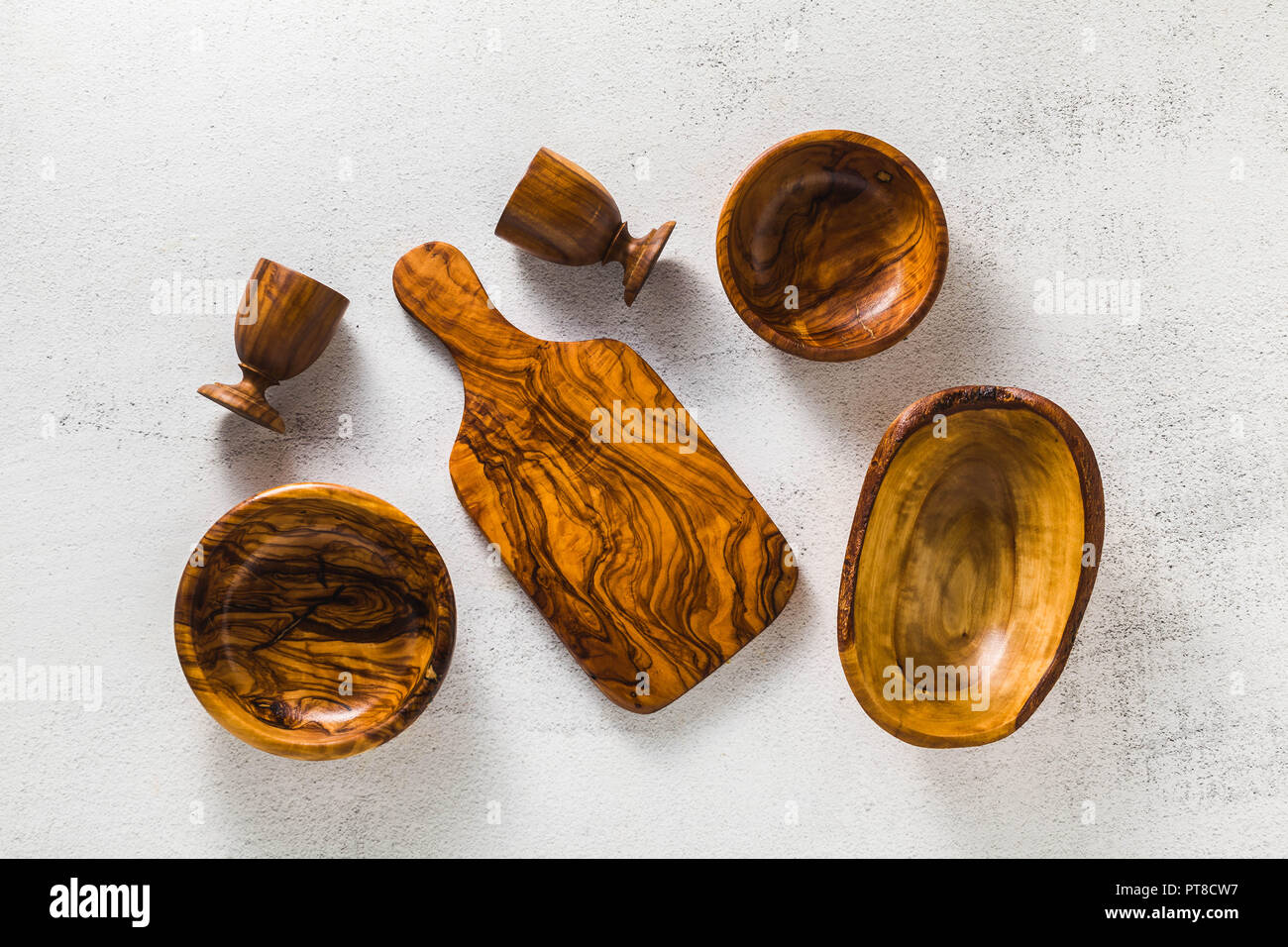 Utensili di legno di ulivo sul bianco tavolo da cucina e i rami di ulivo. eco-friendly kitchenware Foto Stock