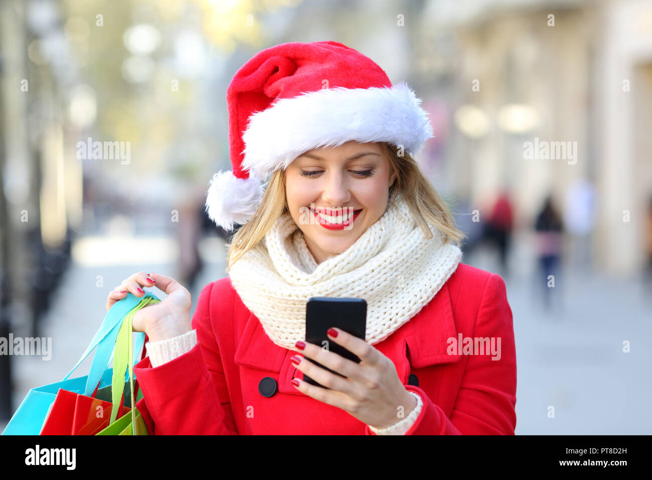 Happy shopper controllo del contenuto del telefono sul Natale in strada Foto Stock