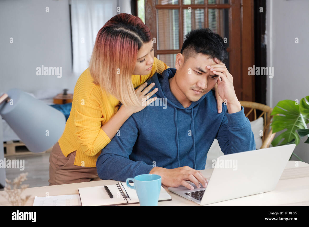 Femmina asiatica ragazza incoraggiamento ragazzo da stress durante il lavoro sul bilancio home su laptop al salotto di casa Foto Stock