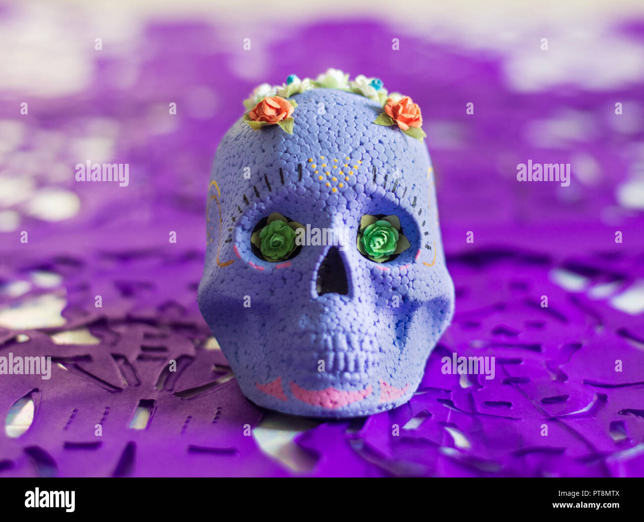 Viola il giorno dei morti il teschio di zucchero, con fiori sulla parte superiore e Viola papel picado (carta tessuto ritagli) come decorazione. Foto Stock