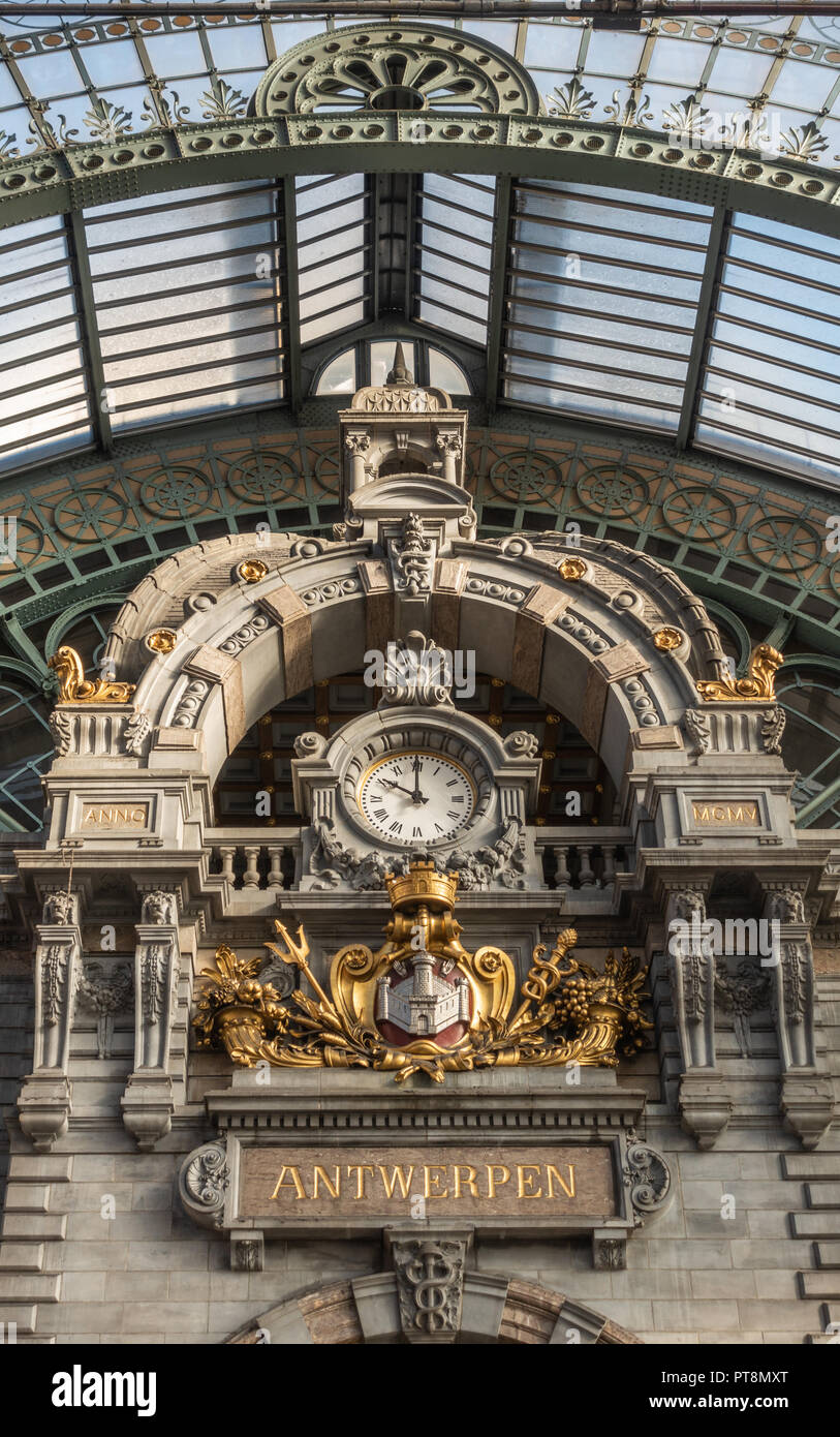Anversa, Belgio - 24 Settembre 2018: Closeup di orologio e stemma della città sul treno facciata hall di Antwerpen Stazione Centrale. Tetto di vetro. Foto Stock