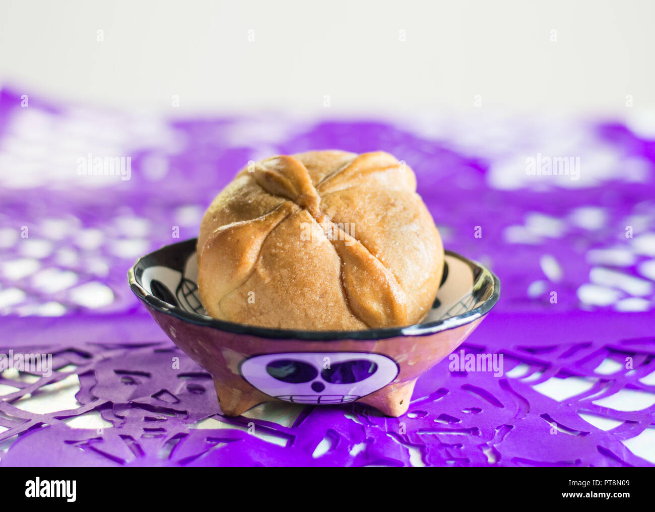 Il giorno dei morti pane tradizionale chiamato pan de muerto e viola papel picado come decorazione. Foto Stock