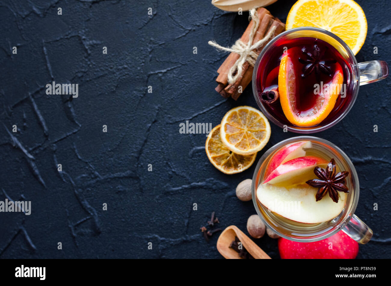 Due bicchieri di diverso tipo di vin brulé o gluhwein sulla base di vino rosso e bianco con spezie e ingredienti su sfondo nero. Caldo speziato bever Foto Stock