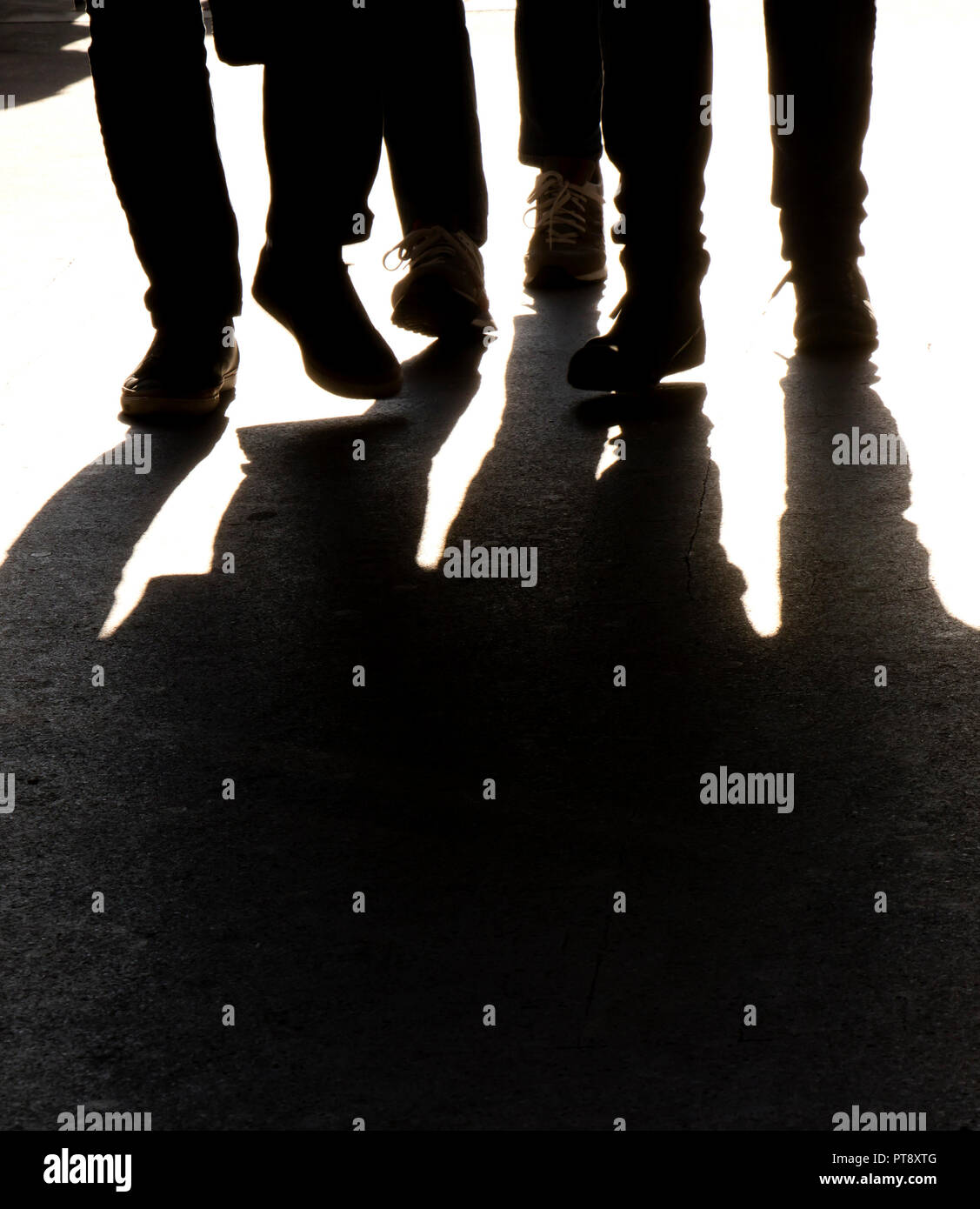 Sagome sfocate e le ombre di gambe di tre persone a piedi, in bianco e nero Foto Stock