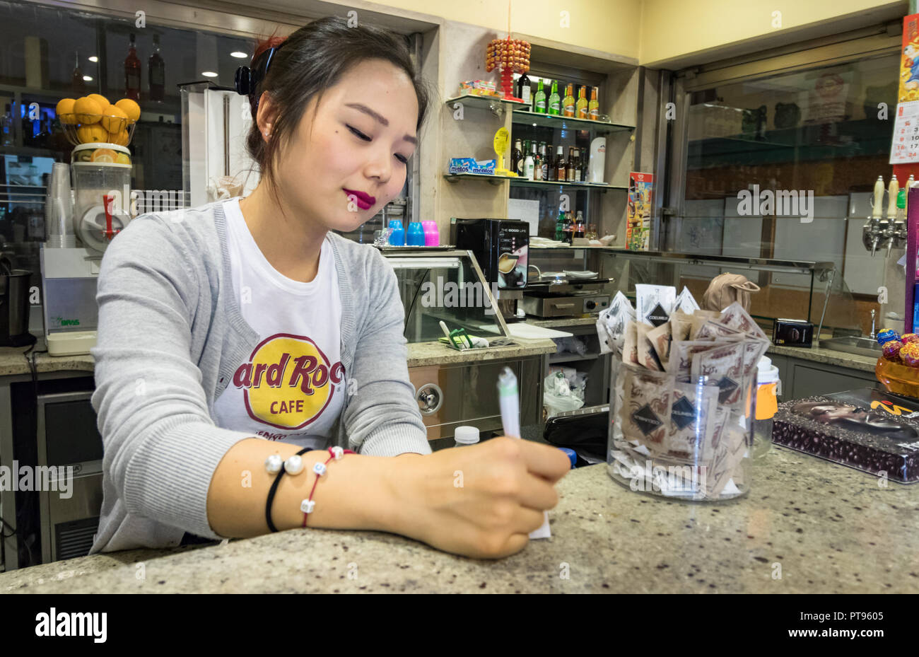 Venezia, Italia - Settembre 26th, 2018: un giovane italiano - donna cinese a lavorare presso il suo negozio di caffè è di scrivere una nota nella notte di Venezia. Foto Stock