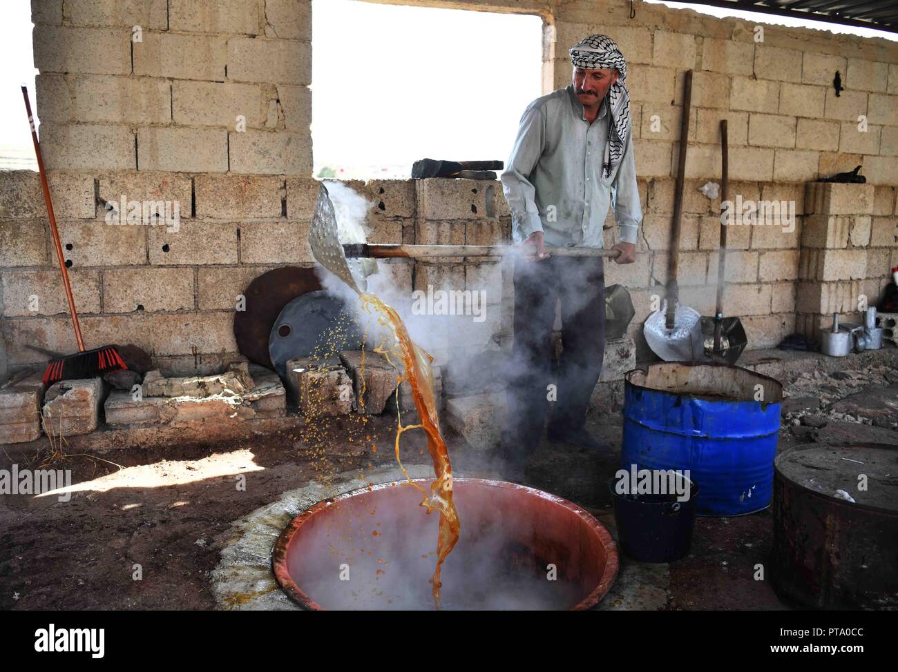 Sweida, Siria. 8 Ott, 2018. Un agricoltore scuote estratto succo d'uva per rendere la melassa di uva in un frutteto in campagna di Sweida, Siria, il 7 ottobre, 2018. Gli agricoltori in provincia Sweida nel sud della Siria, che è noto per essere uno dei migliori e più dolce delle uve nel paese, sono accoglienti la stagione del raccolto di uve ogni anno intorno a questo tempo per rendere il melasso di uva, il cibo tradizionale che ha mantenuto la sua popolarità nel sud della Siria. Credito: Ammar Safarjalani/Xinhua/Alamy Live News Foto Stock