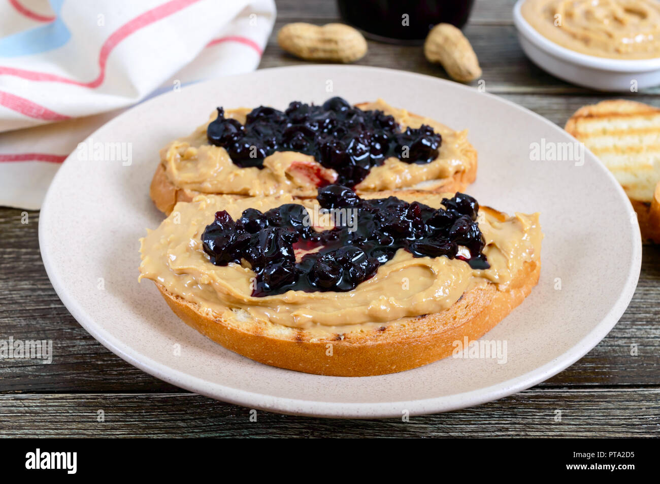 Fette biscottate con burro di arachidi e marmellata di frutti di bosco su  una piastra su un tavolo di legno. Una colazione nutriente. Gastronomia  americana Foto stock - Alamy