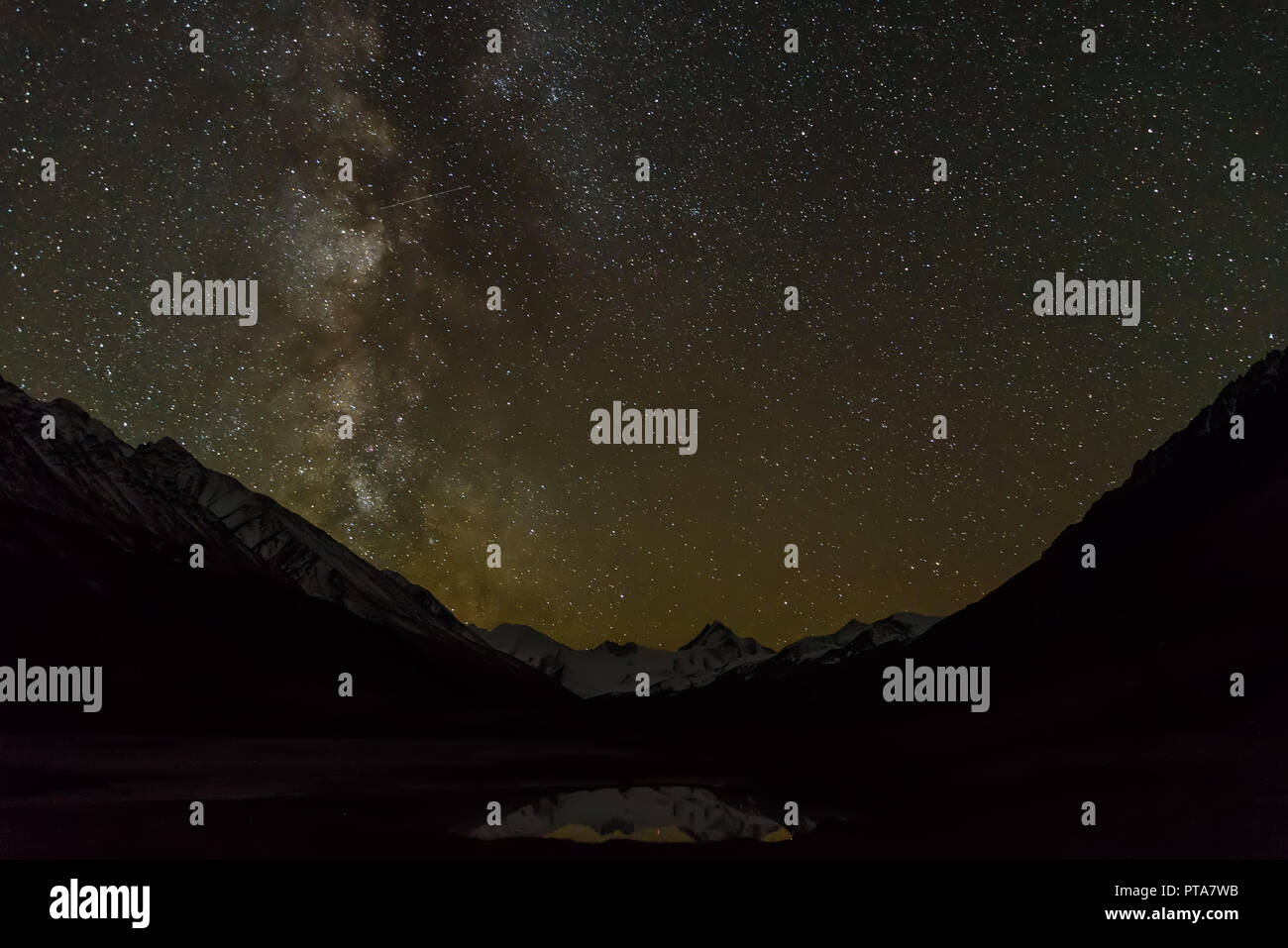 Bellissimo paesaggio notturno con un cielo stellato la Via Lattea oltre le montagne innevate e riflessi nel lago Foto Stock