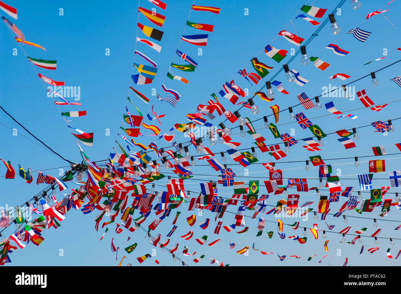 Bandiere del mondo in forma di bunting su più linee che conducono ad una centrale di pinta contro un cielo blu chiaro Foto Stock