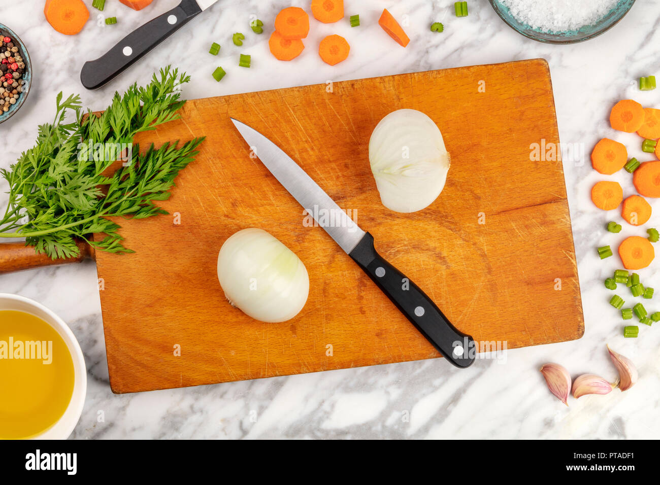 Tempo di preparazione o di mise en place. Una foto aerea di uno chef professionale il coltello, ripresa dall'alto su un tagliere con un trito di verdure e spezie, sul marmo di un piano di cottura con spazio di copia Foto Stock