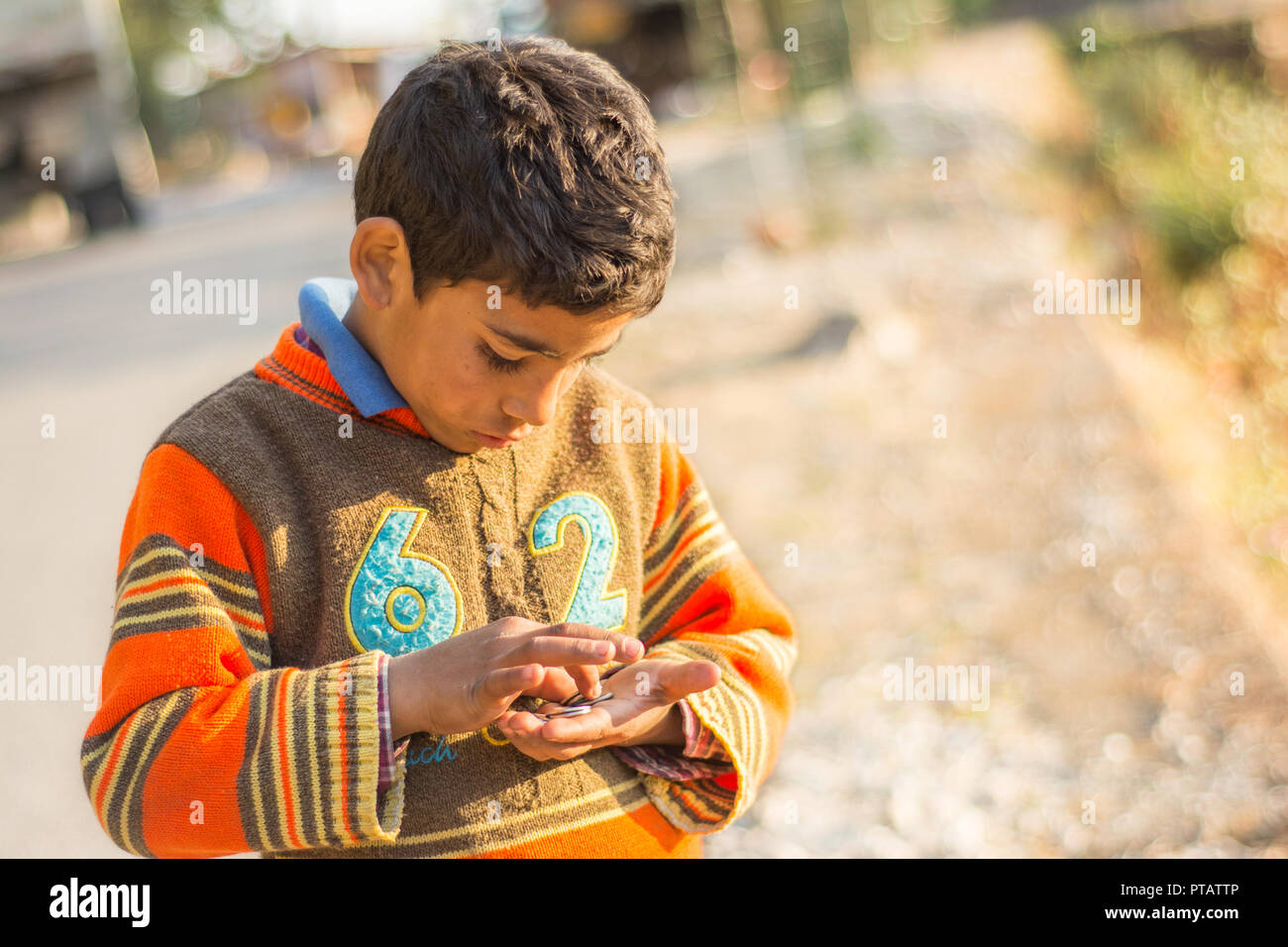 La foto di un ragazzo indiano guardando verso il basso e contare monete nelle sue mani nel pomeriggio a Mussourie, Uttarakhand Foto Stock