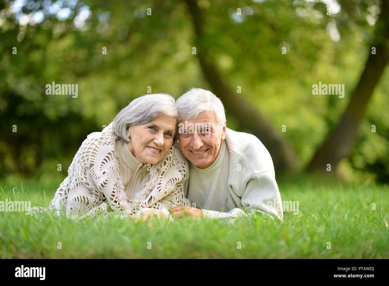 Ritratto di coppia di anziani giacente su erba verde in estate park Foto Stock