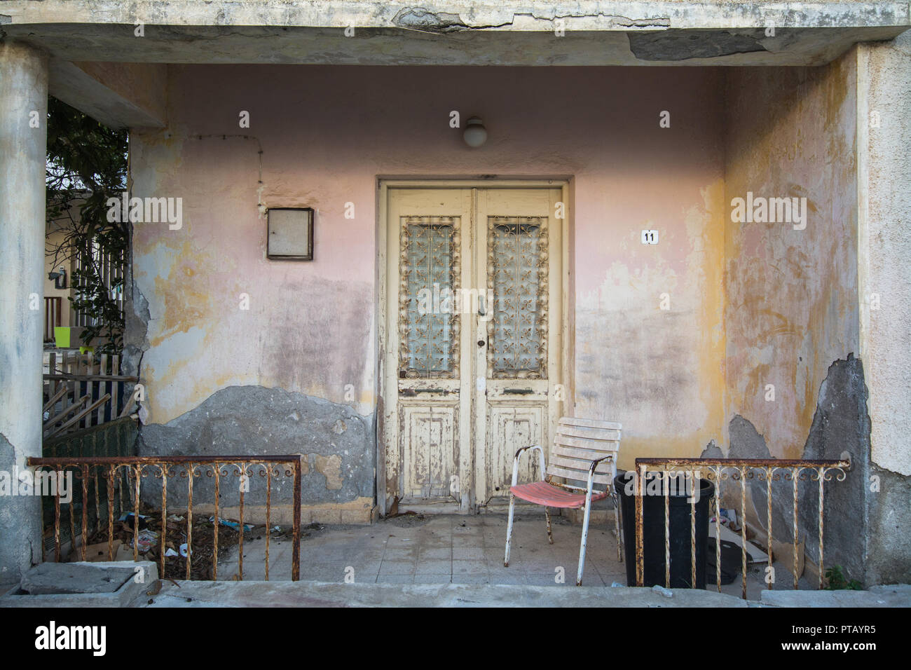 Portico frontale di una casa diroccata proprietà con lo sfaldamento o sbriciolamento gesso nella città di Paphos, Cipro Foto Stock