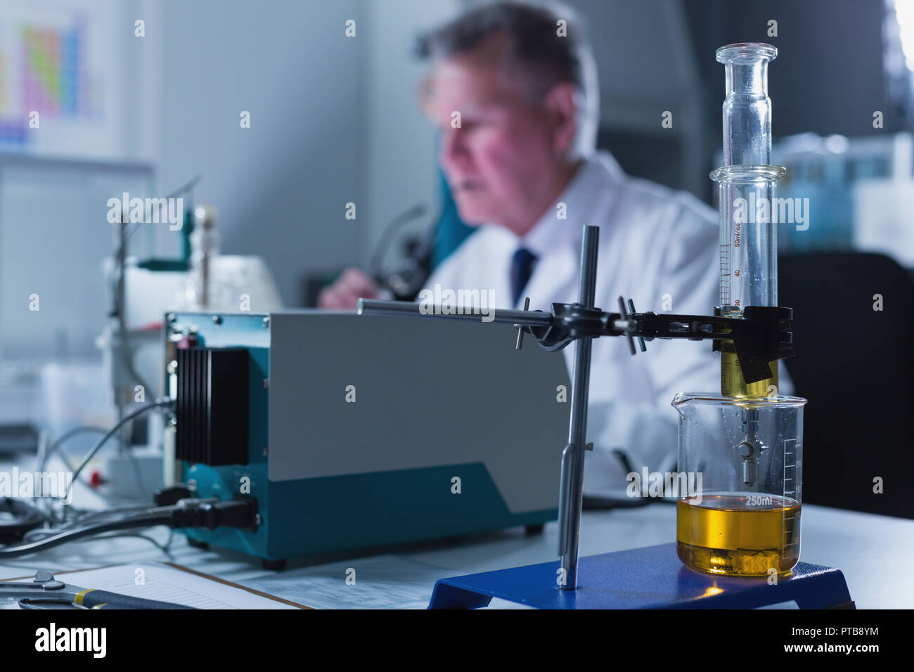 Siringa in vetro con supporto e bicchiere disposto sulla tavola in laboratorio Foto Stock