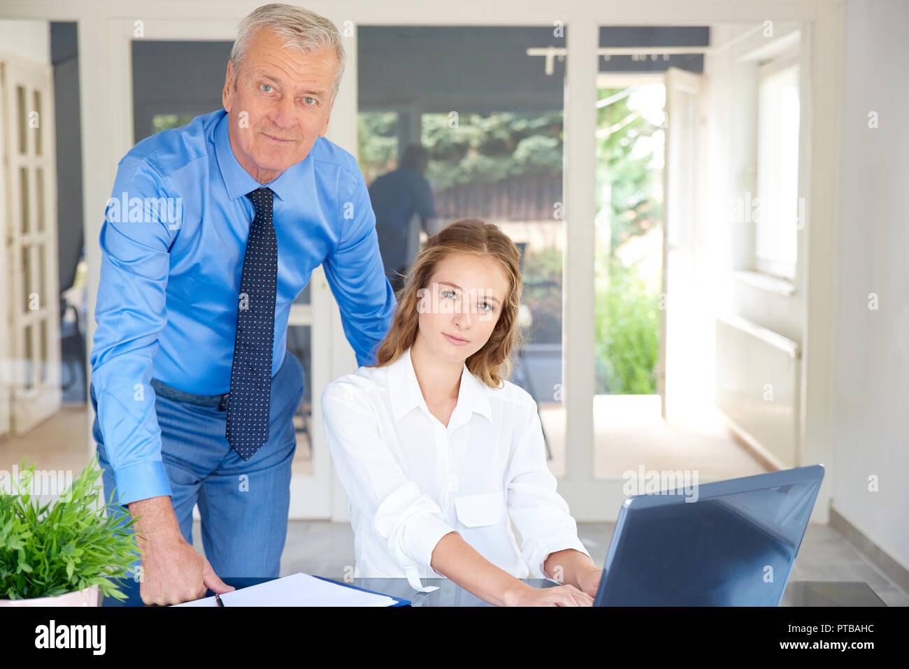 Colpo di giovani e senior business persone che lavorano insieme in ufficio. Giovane donna di vendita utilizzando notebook mentre imprenditore senior dando il suo alcuni adv Foto Stock