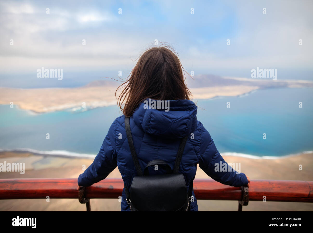 Vista posteriore del viaggiatore donna godendo di bellissimi paesaggi marini di La Graciosa isola a Viewpoint. Concetto di viaggio. Inverno in Isole Canarie Foto Stock