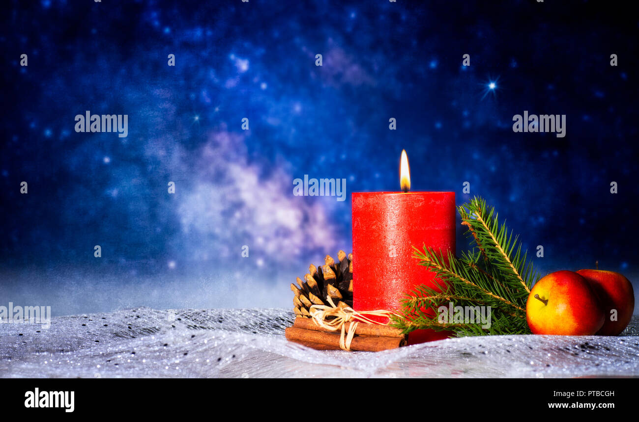 Candela rossa con decorazioni natalizie, cielo stellato e spazio di copia Foto Stock
