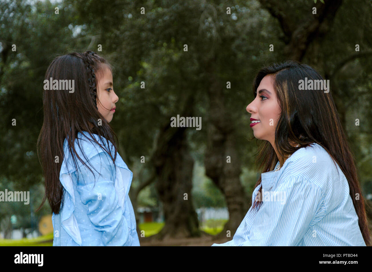 Sua madre e la sua piccola figlia guardando ogni altro su un pomeriggio d'inverno nel Parco Foto Stock