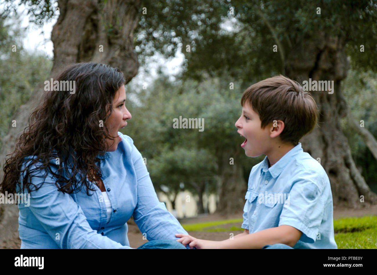 Bella donna e il suo grazioso piccolo figlio cercando di ogni altro stupiti nel parco Foto Stock