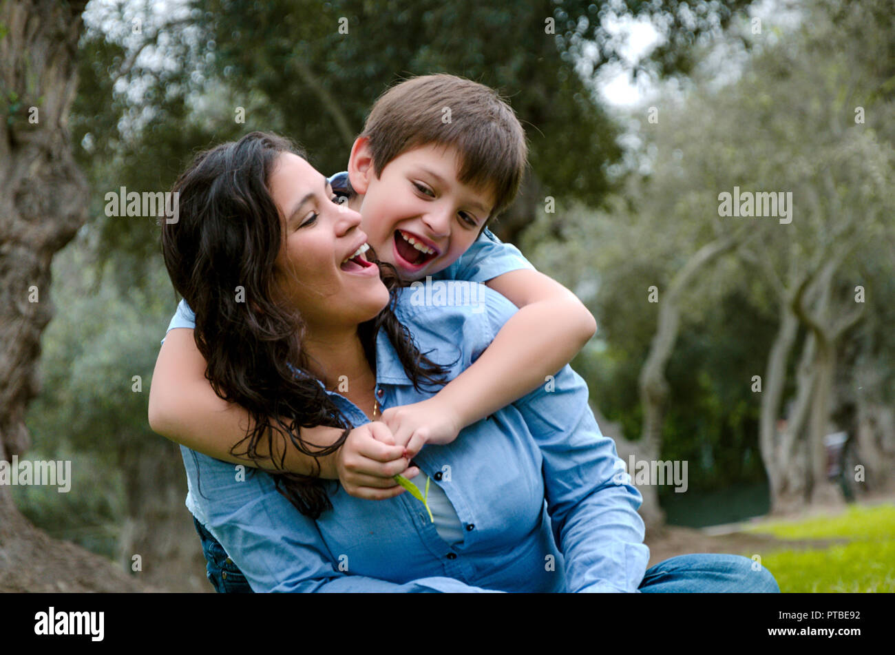 Bambino abbraccia la madre sorridente in un pomeriggio autunnale nel Parco Foto Stock