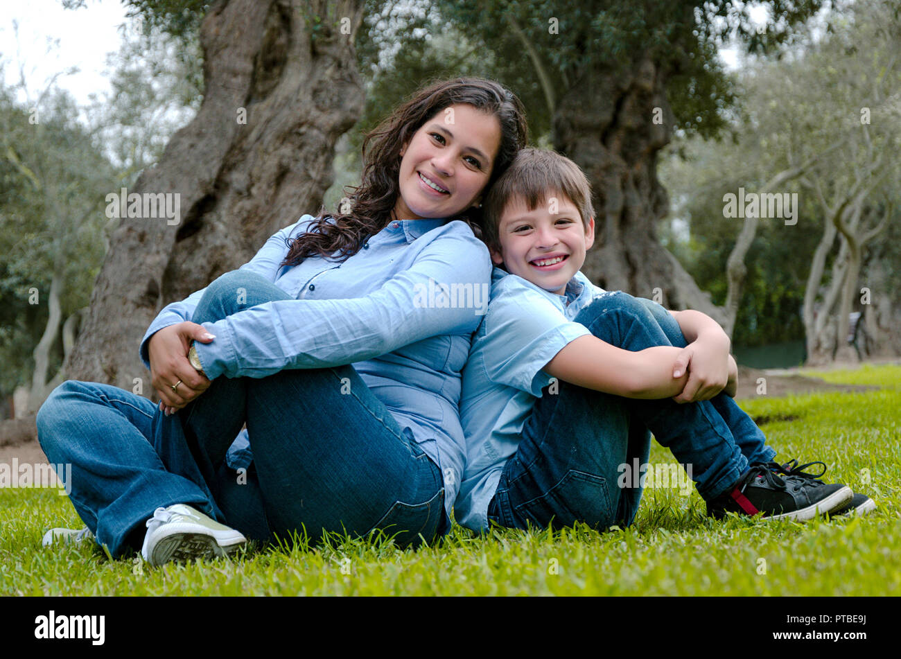 Madre e figlio seduti su erba verde nel parco verde. Concetto di famiglia felice relazioni e spensierato tempo libero Foto Stock