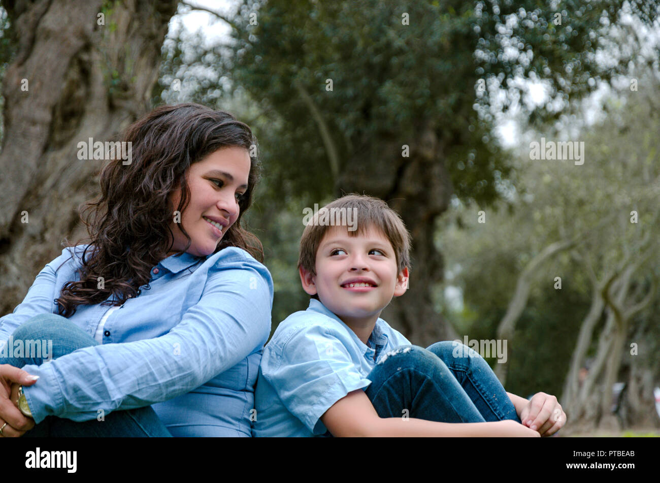 Madre e figlio seduti su erba verde nel parco verde. Concetto di famiglia felice relazioni e spensierato tempo libero Foto Stock