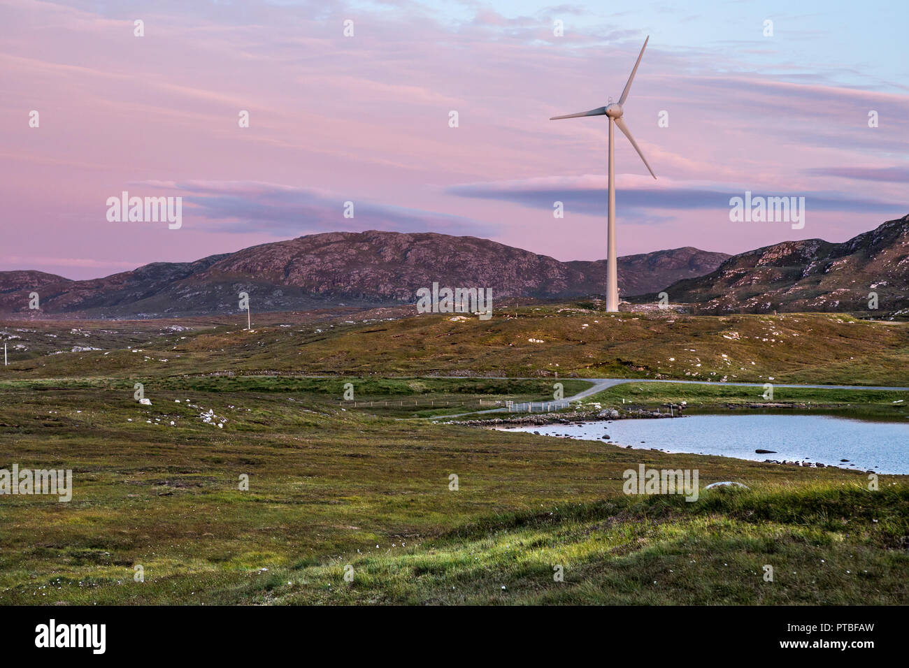 Una turbina eolica nel bellissimo paesaggio scozzese panorama al tramonto con il cielo rosa, isola di Lewis, Ebridi Esterne, Scotland, Regno Unito Foto Stock