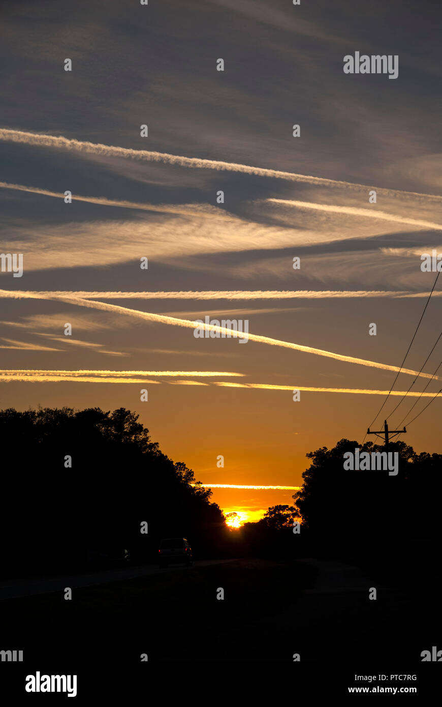 Jet contrails attraversano il cielo al tramonto in North Central Florida. Foto Stock