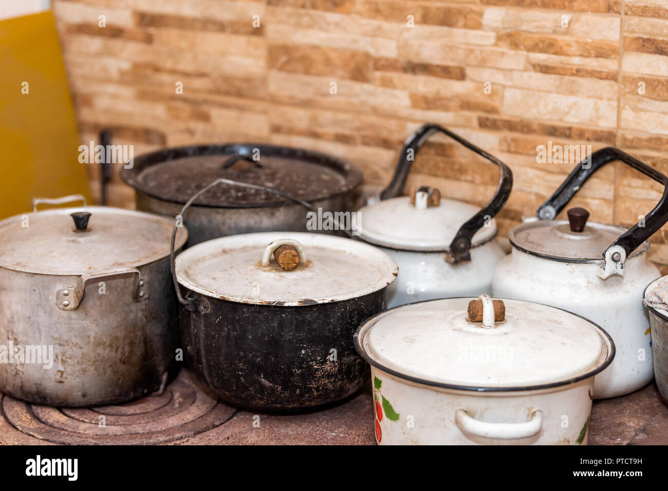 Molti grandi pentole e padelle su rustiche dacha paese casa o casa cottage fornello da cucina con sporcizia, forno a legna, mattone parete backsplash Foto Stock