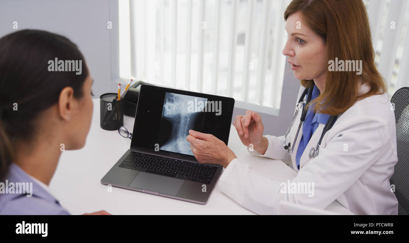 Stretto colpo di mezza età medico rivedendo i raggi x dei pazienti collo all'interno di office Foto Stock