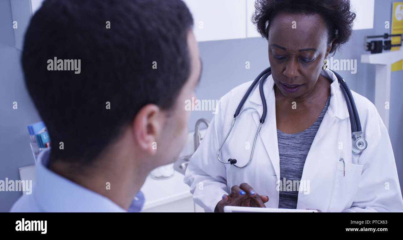 Stretto colpo di African medico donna spiegando al paziente giovane condizioni di salute Foto Stock