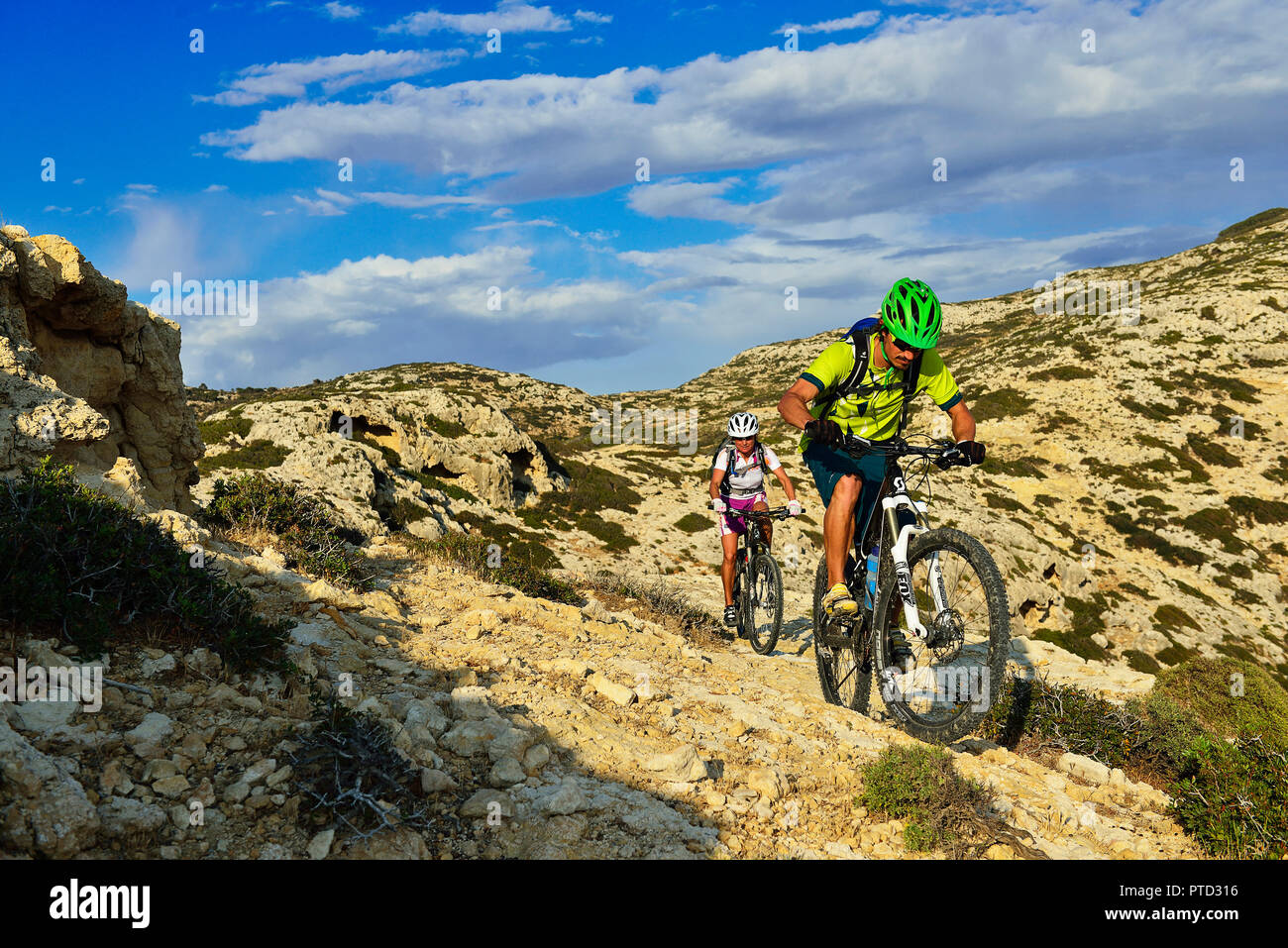 Due mountain bikers ciclo nel terreno roccioso, Red Beach, Matala, Creta, Grecia Foto Stock