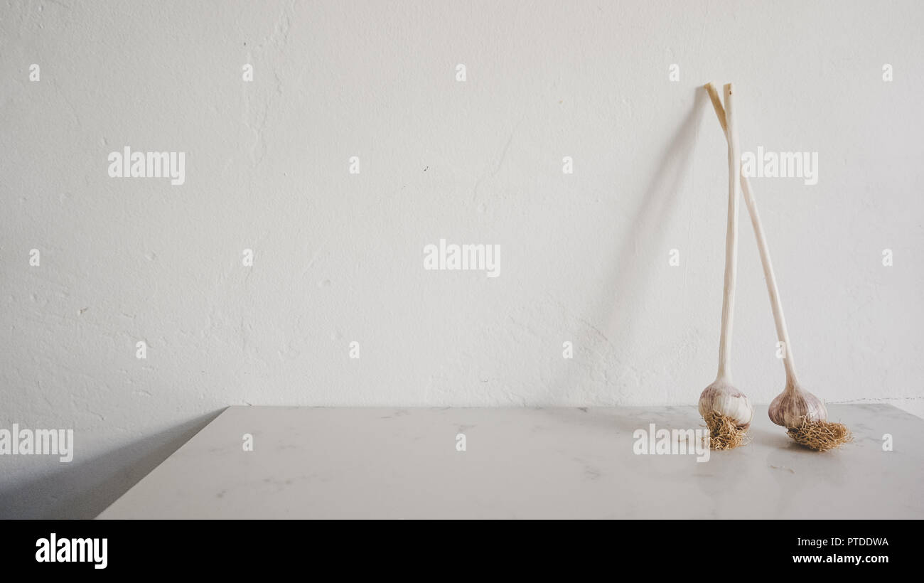 Lungo organico con gambo aglio crudo sul bancone di marmo in una cucina da gourmet. Azienda agricola alla tavola concept Foto Stock