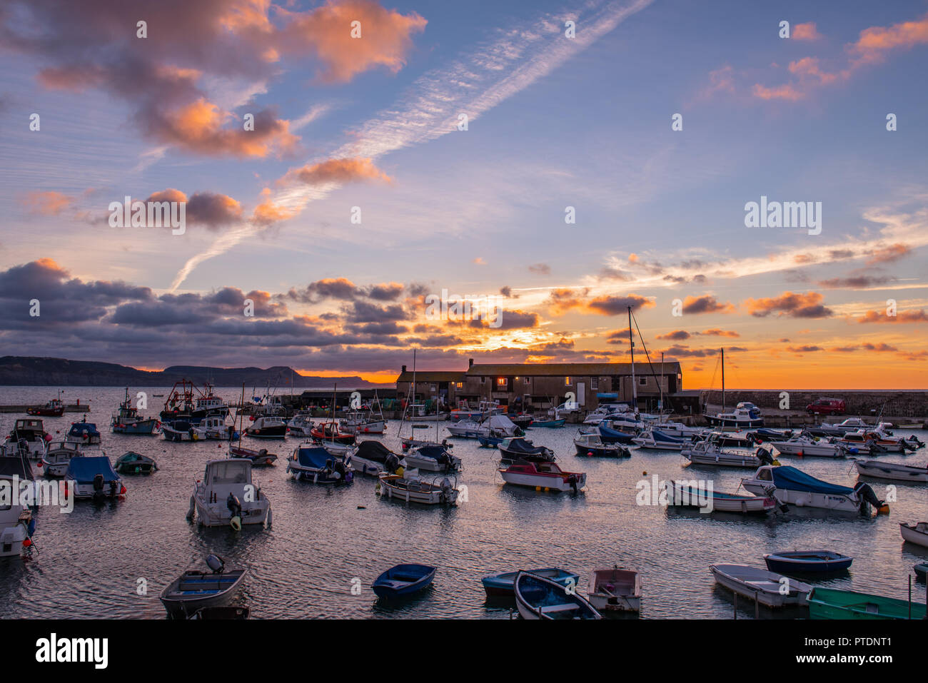 Lyme Regis, Dorset, Regno Unito. Il 9 ottobre 2018. Regno Unito Meteo: Moody mattina nuvole come sunrise colori illuminano il cielo sopra il Cobb, Lyme Regis. Credito: Celia McMahon/Alamy Live News Foto Stock