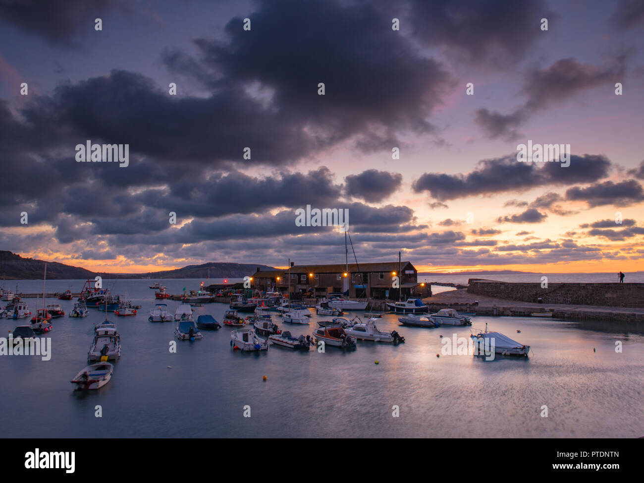 Lyme Regis, Dorset, Regno Unito. Il 9 ottobre 2018. Regno Unito Meteo: Moody mattina nuvole come sunrise colori illuminano il cielo sopra il Cobb, Lyme Regis. Credito: Celia McMahon/Alamy Live News Foto Stock