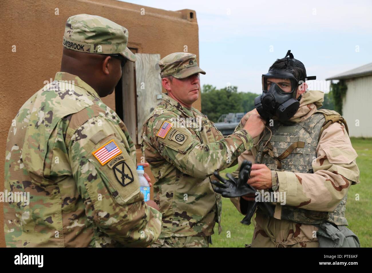 Stati Uniti Il personale dell'esercito Sgt. Kevin Smith, xx comando CBRNE, assiste Cpl. Contrassegnare i pettini, 52nd Ordnance Gruppo (EOD), togliere il suo servizio comune leggero tuta integrato di tecnologia, Aberdeen Proving Ground, Md., luglio 11, 2017. Il ventesimo CBRNE guerriero migliore concorrenza è una divisione concorso di livello che sarà in grado di identificare un soldato e uno non ufficiale incaricato di procedere a FORSCOM del guerriero migliore concorrenza. Foto Stock