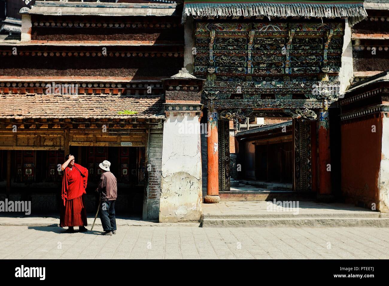 Monastero di Labrang, Xiahe, provincia di Gansu / Cina - 6 GIU 2011: un monaco tibetano sta parlando con un uomo pellegrino di fronte al tempio con eccezionale de Foto Stock