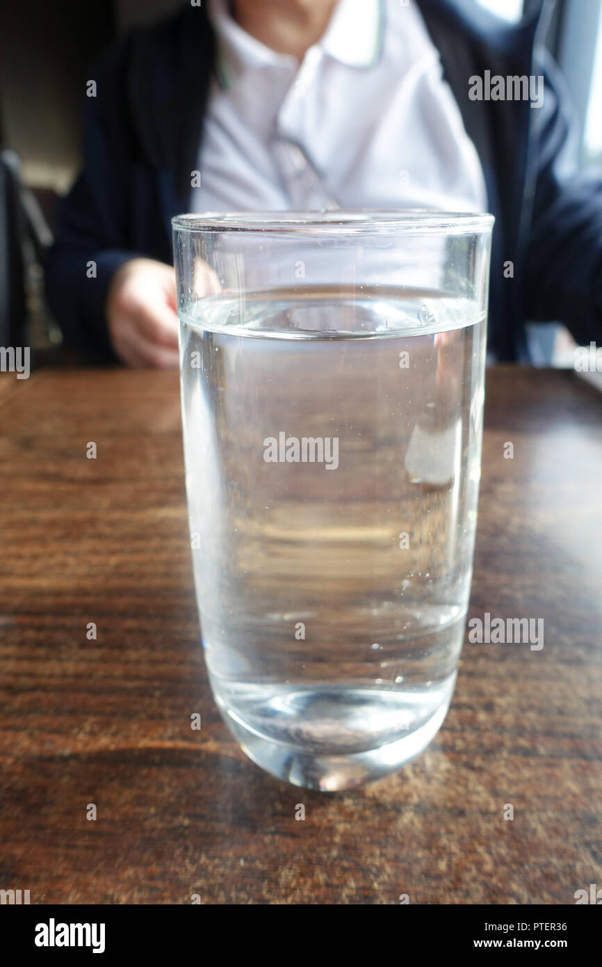 Un bicchiere di acqua su un tavolo di legno Foto Stock