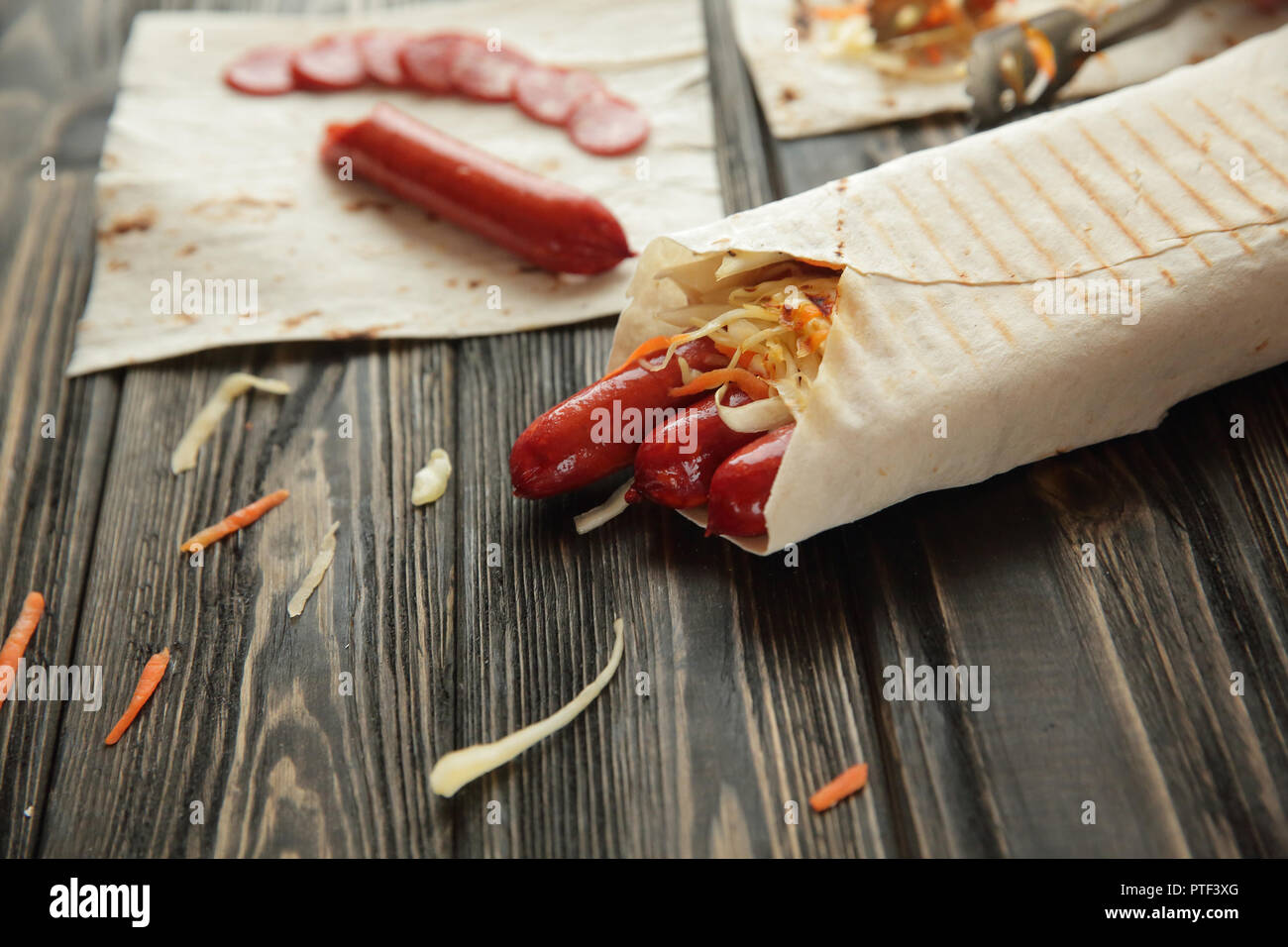 Salsiccia affumicata in pane pita su sfondo di legno Foto Stock