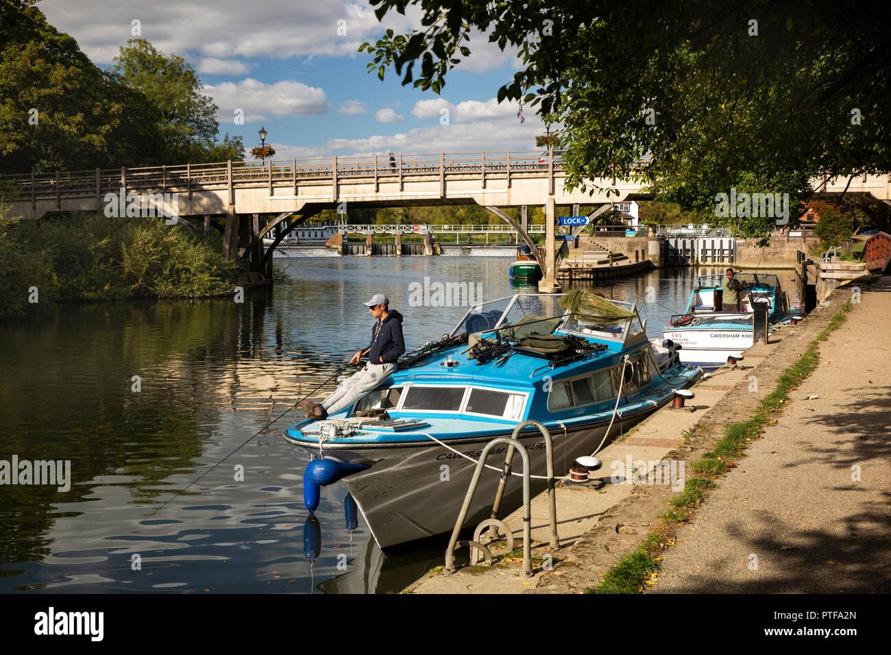 Inghilterra, Berkshire, Goring sul Tamigi, il pescatore pesca dalla barca ormeggiata sul Fiume Tamigi da serrature e ponte a Streatley Foto Stock