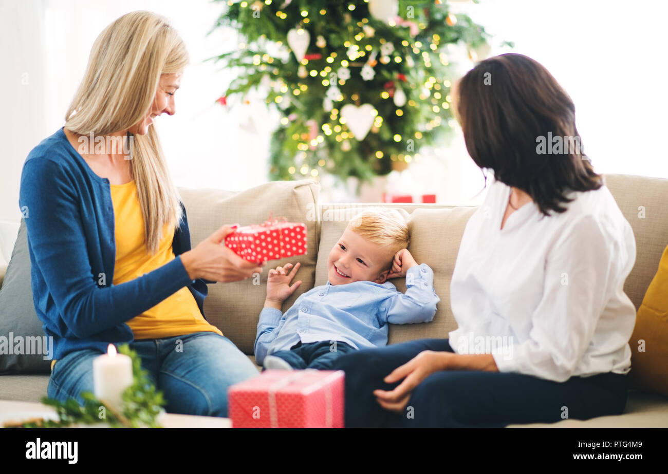 Una madre e nonna dando presenta ad un ragazzino di casa al tempo di Natale. Foto Stock